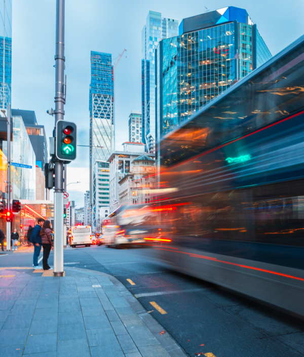 A city intersection featuring traffic lights and a bus in motion amidst tall buildings.