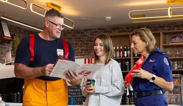 A firefighter, a woman, and a paramedic discussing a menu at a café.