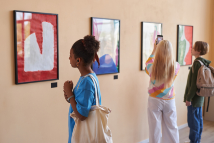 Visitors in a gallery looking at abstract artwork displayed on the walls.